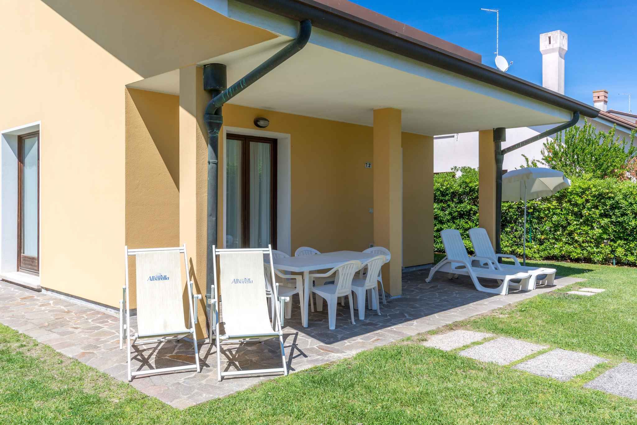 Un'area esterna riparata con un tavolo e sedie, una poltrona bianca e un cartello con la scritta "Alberella".