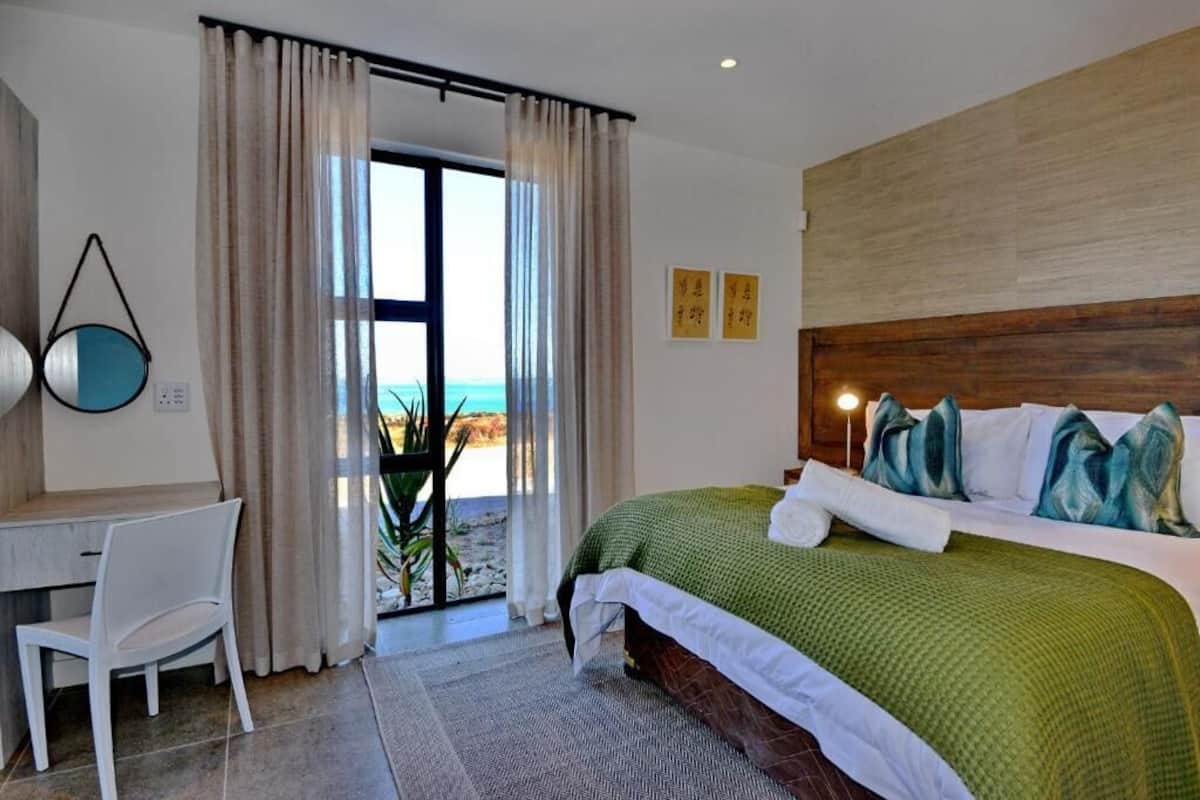 Un dormitorio con cama, escritorio y vista a la playa.