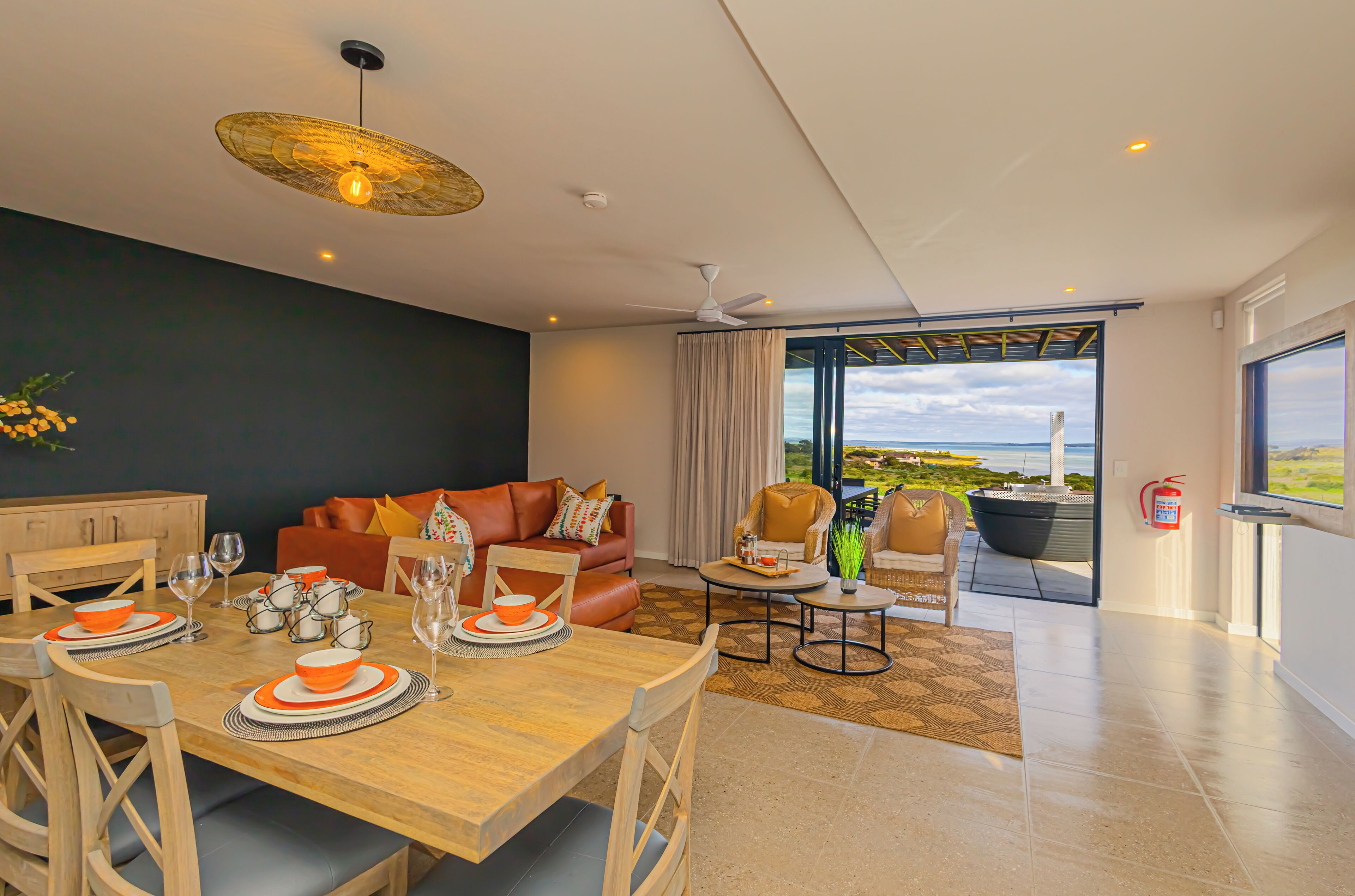 A modern living room with a dining area, a sofa, and a view of the outdoors.
