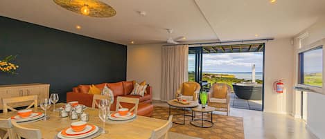 A modern living room with a dining area, a sofa, and a view of the outdoors.