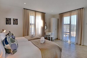 Habitación de hotel con dos camas, un escritorio y una silla.