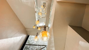 A staircase with a modern design, featuring a glass railing and a series of hanging pendant lights. - The Orbit Regency (Gangtok)