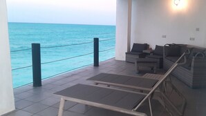 A balcony with a view of the sea, a wicker sofa, a small table, and a chair. - Game Fish Apartment (Nungwi)
