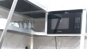 A compact kitchen with a microwave, kettle, and utensils on a white countertop. - Game Fish Apartment (Nungwi)
