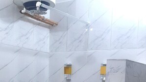 A bathroom with marble walls, a shower area, and a tiled floor. - Game Fish Apartment (Nungwi)