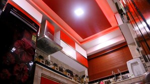 Una cocina con una decoración en rojo y blanco, electrodomésticos de acero inoxidable y una lámpara de techo roja.