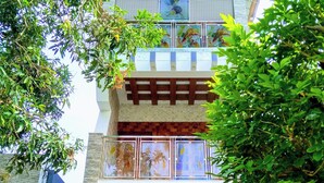 Un edificio de varios pisos con un balcón, una puerta de madera y una ventana con una reja decorativa.