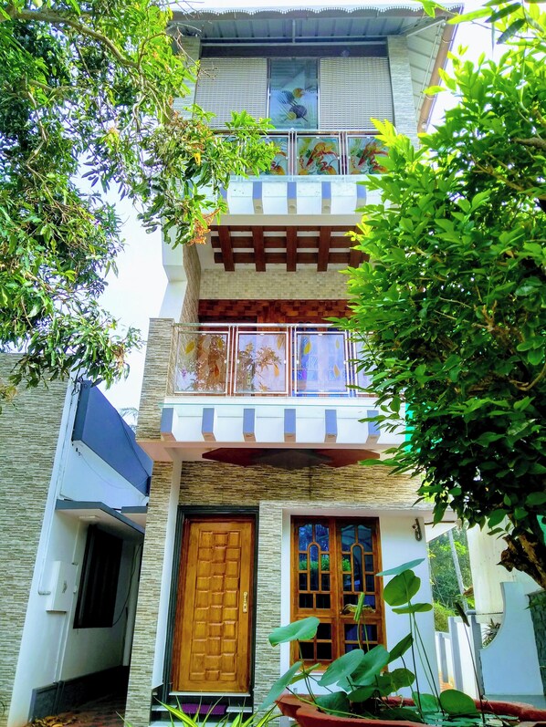 Un edificio de varios pisos con un balcón, una puerta de madera y una ventana con una reja decorativa.