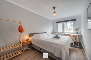 Relax in a spacious bedroom with a large bed, a convenient storage rack, and a comfortable reading nook by the window.