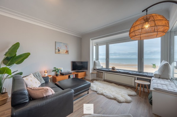 Relax in this stylish living room with a sofa, armchair, and floor-to-ceiling window overlooking the sea.
