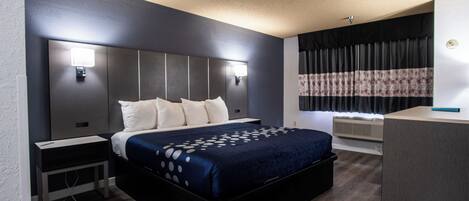A modern hotel room with a large bed, bedside tables, a desk, and a window with curtains.