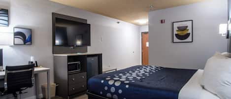Una habitación de hotel con cama, escritorio y televisor.