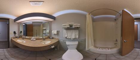 A bathroom with a sink, mirror, toilet, and shower.