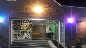 Un edificio con fachada de ladrillo, un muro decorado y una escalera que conduce a la entrada.