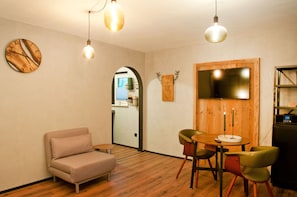 Um quarto aconchegante com sofá, mesa redonda com cadeiras, decoração de parede em madeira e um relógio.