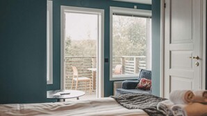 Un dormitorio con cama, ventana y vistas a una zona de estar exterior.