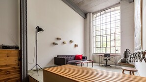 Una sala moderna con un banco de madera, un sofá, un escritorio y un ventanal grande.