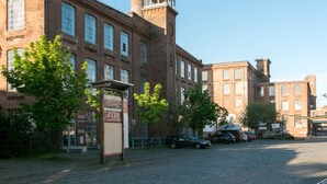 Un edificio histórico de ladrillo con ventanas grandes y una chimenea alta.