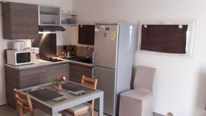 Une cuisine compacte équipée d’un four à micro-ondes, d’une cuisinière, d’un réfrigérateur et d’une table à manger avec des chaises.