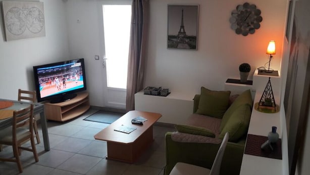 Un salon comprenant un téléviseur, un canapé, une table basse et un coin repas avec des chaises.