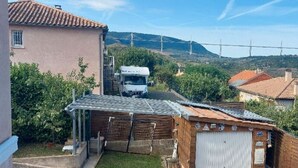 Un paysage rural avec un camion blanc garé devant un bâtiment dont le toit est fait de tôles ondulées.