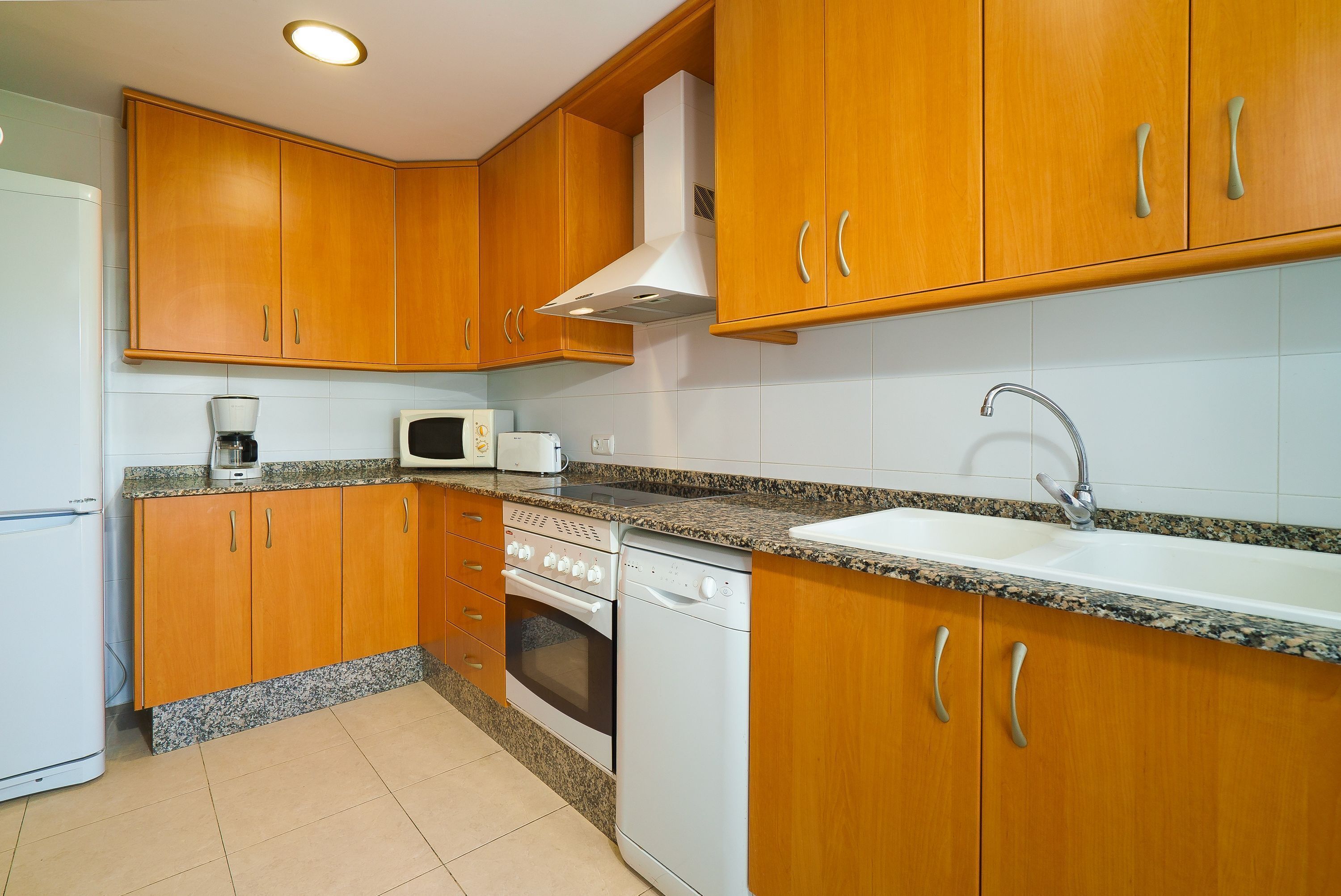 A kitchen with wooden cabinets, a microwave, a stove, a dishwasher, and a sink.