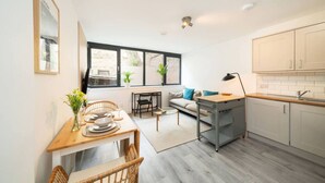 A modern kitchen with a dining area, a sofa, and a window with plants. - Castle Street Apartment - stylish city centre pad (Dundee)