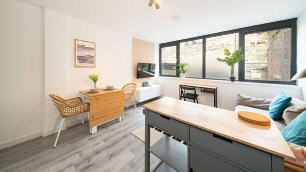 A modern kitchen with a dining area, large windows, and a television. - Castle Street Apartment - stylish city centre pad (Dundee)