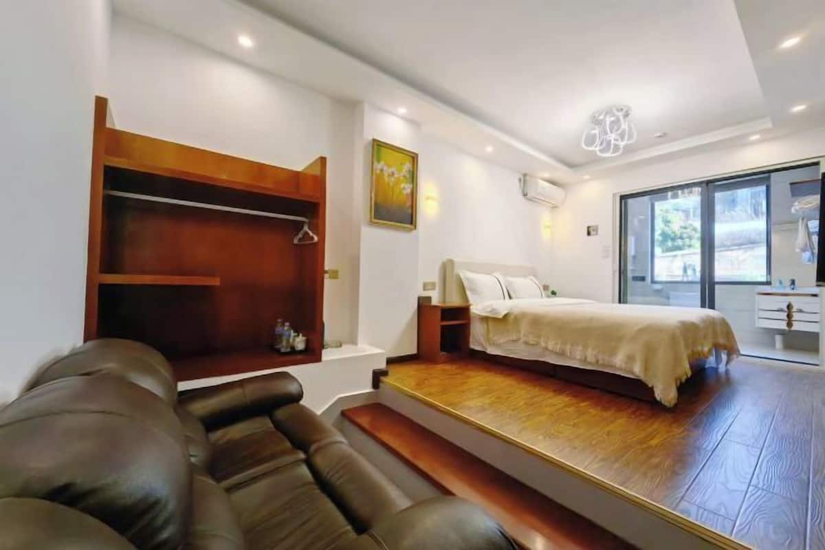 Ein Schlafzimmer mit einem Bett, einer Sitzecke, einem Holzregal und einem Fenster.