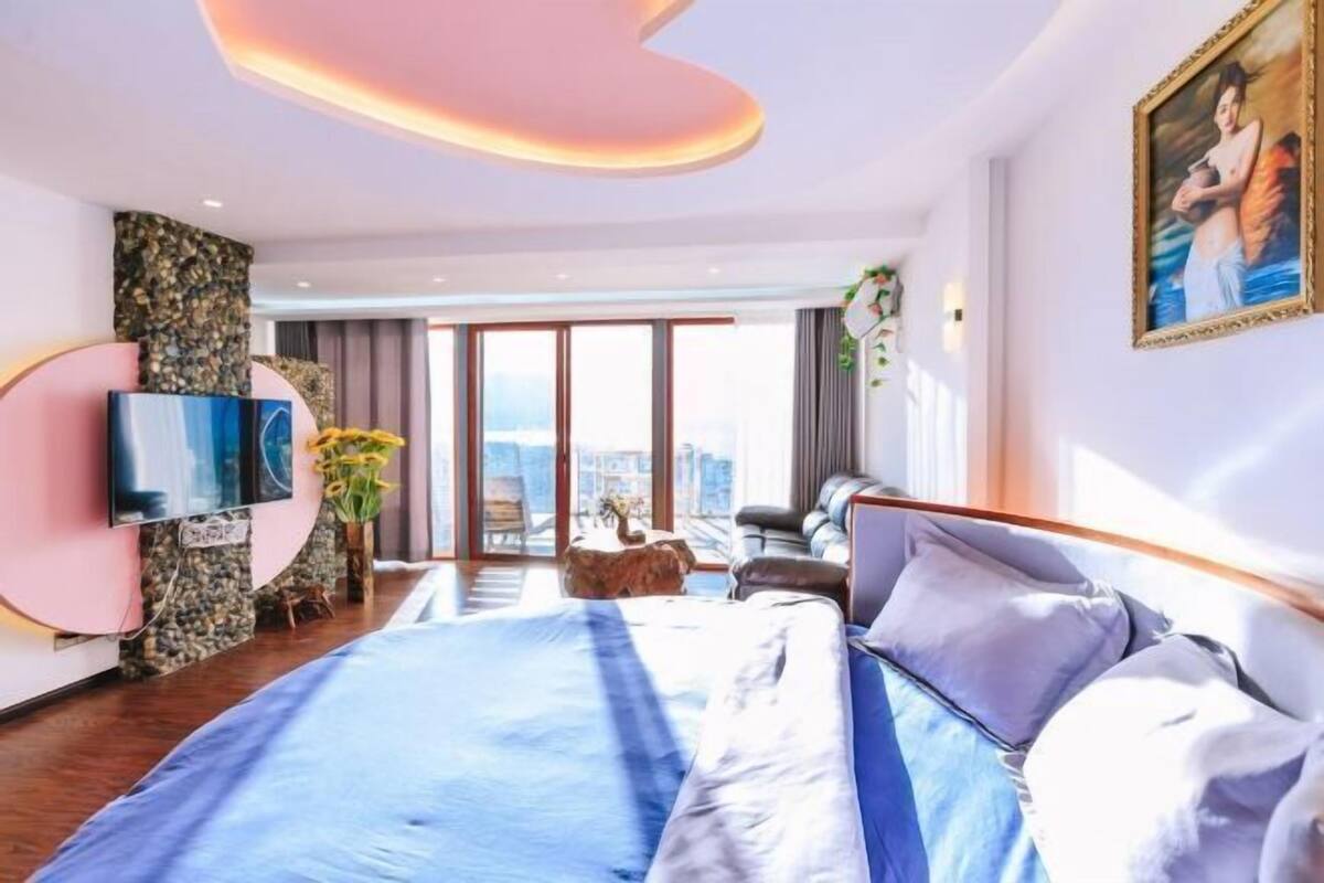 Ein modernes Hotelzimmer mit einem großen Bett, einem Flachbildfernseher, einer Wand mit Steinakzenten und Blick auf die Stadt.