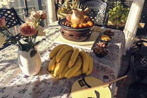 A table with a floral tablecloth, a vase with flowers, a plate of bananas, and a bowl of fruits. - Banshan Guest Seaview Holiday Villa (Dali City)