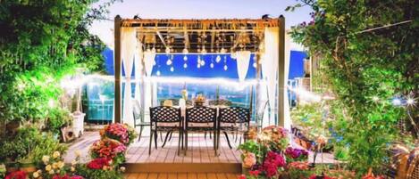 An outdoor patio with a wooden deck, a table with chairs, and potted plants.