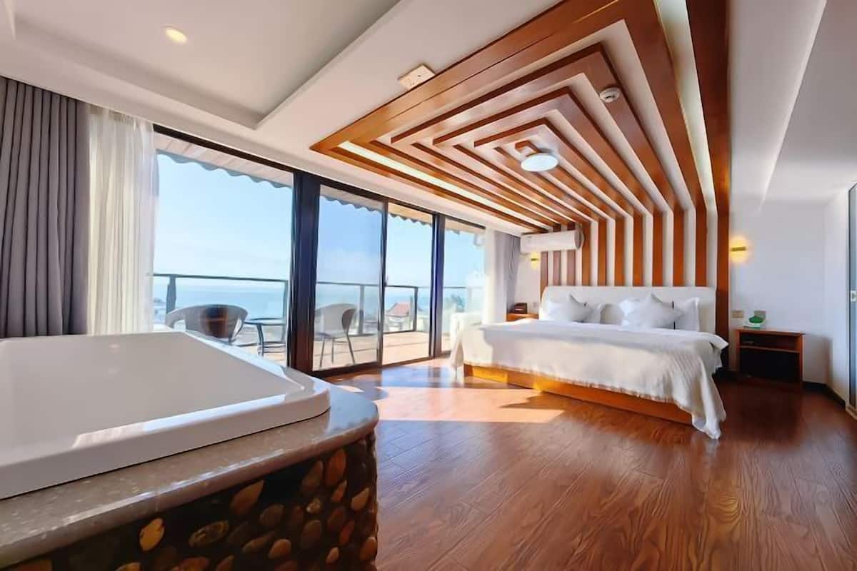 Ein modernes Hotelzimmer mit einem großen Bett, einer Badewanne und einem Balkon mit Blick.