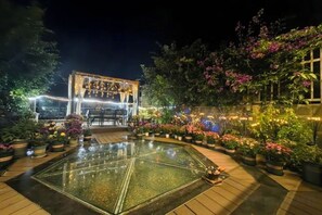 An outdoor garden area with a glass-topped table, surrounded by potted plants and a decorative archway. - Banshan Guest Seaview Holiday Villa (Dali City)