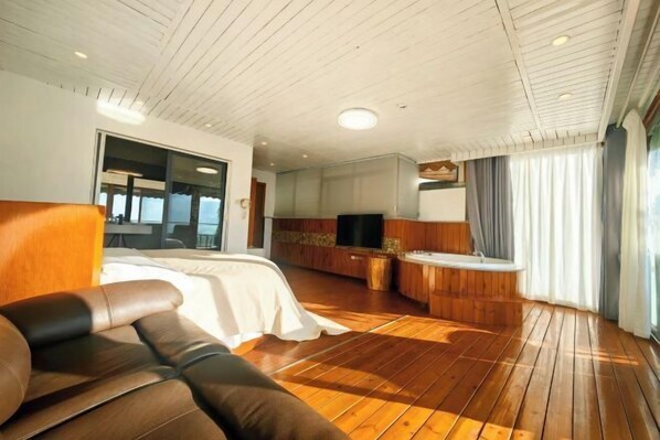 A room with a bed, a sofa, a TV, a wooden floor, and a window with curtains. - Banshan Guest Seaview Holiday Villa (Dali City)