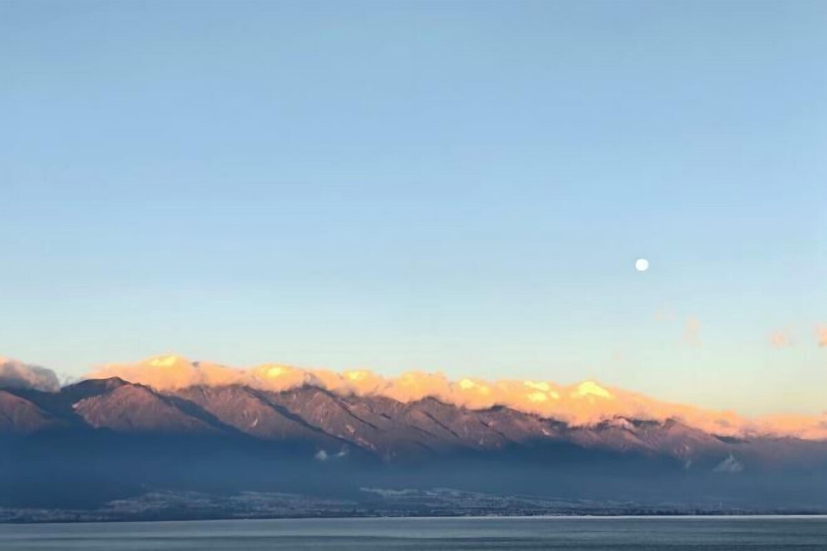A mountain range with a clear sky and a visible moon.