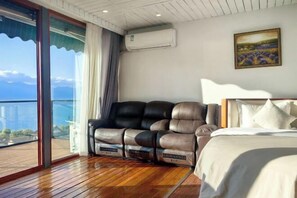 A bedroom with a bed, a leather sofa, and a large window with a view of the sea. - Banshan Guest Seaview Holiday Villa (Dali City)