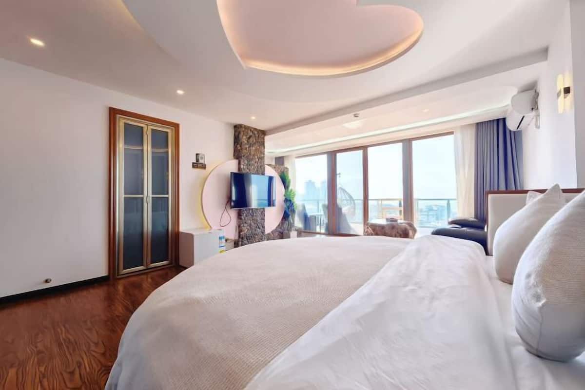 Ein Hotelzimmer mit einem großen Bett, einem Fernseher, Blick auf die Stadt und einem modernen Deckenstil.