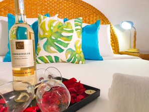 A hotel room with a bed, a bottle of Connaisseur wine, a tray with rose petals, and a candle. - Green Nha Trang (Nha Trang)