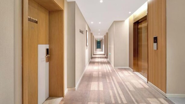Passadís d'hotel modern amb portes de fusta, terra amb moqueta i il·luminació empotrada.