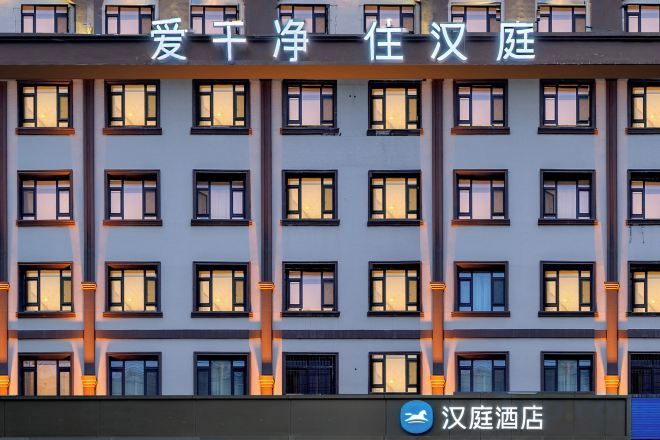 Een gevel van een gebouw met meerdere ramen en een bord waarop een hotel wordt aangegeven.