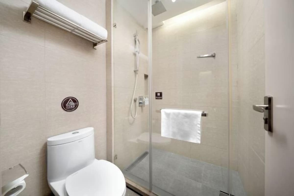 A modern bathroom with a toilet, a glass shower enclosure, and a towel rack.