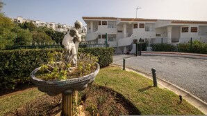 A statue in a garden with a white building in the background. - Arte De Luz in Urbanizaci n Riviera Sol (Mijas)