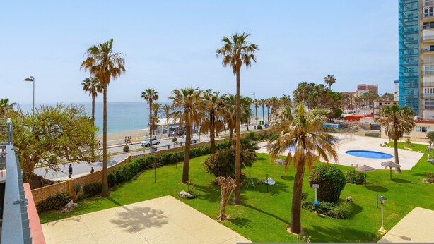 A view of a landscaped area with palm trees, a pool, and a beach in the background. - Garceta in Benalmadena (Benalmádena)