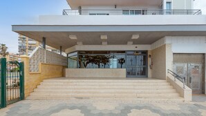 A building entrance with a set of stairs leading up to a gated door, a covered walkway, and a tiled ground. - Garceta in Benalmadena (Benalmádena)