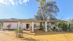 A single-story building with a tiled roof, a covered patio area, and several potted plants. - Casa Rural Los Menestrales (Lora Del Rio)