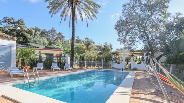 A rectangular swimming pool with a metal ladder, surrounded by lounge chairs and a hammock. - Casa Rural Los Menestrales (Lora Del Rio)