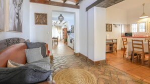A cozy living room with a sofa, a patterned rug, and a dining area with a table and chairs. - Casa Rural Los Menestrales (Lora Del Rio)