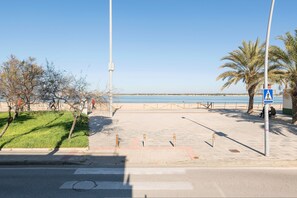 A coastal promenade with a pedestrian walkway, palm trees, and a clear view of the sea. - Atardecer En Sanl car (Sanlucar de Barrameda)