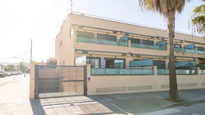 A multi-story building with a gated entrance, a palm tree, and a clear sky.